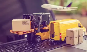 Miniatura ciężarówki, wózka widłowego i samolotu na klawiaturze z pudełkami.