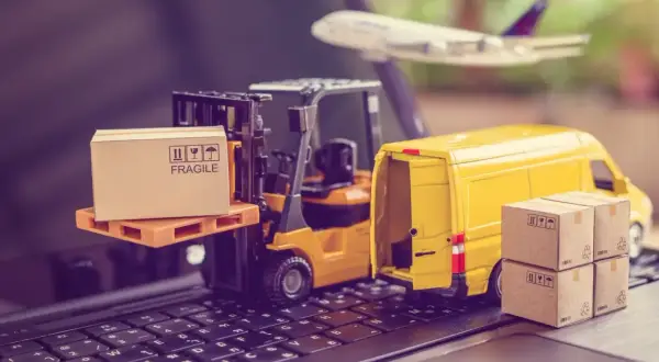 Miniatura ciężarówki, wózka widłowego i samolotu na klawiaturze z pudełkami.