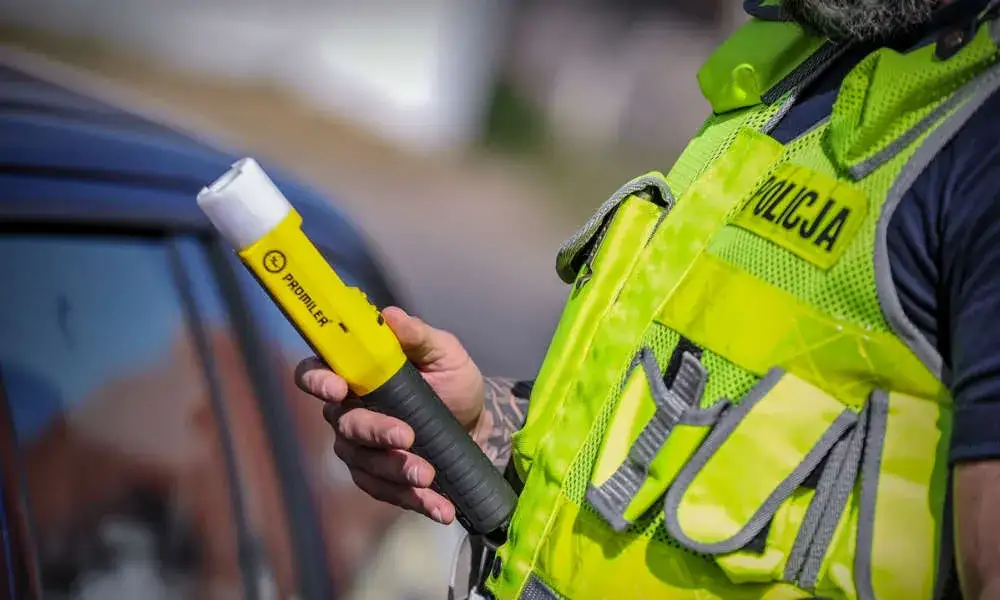 policjant używający alkomatu świeczka podczas kontroli drogowej