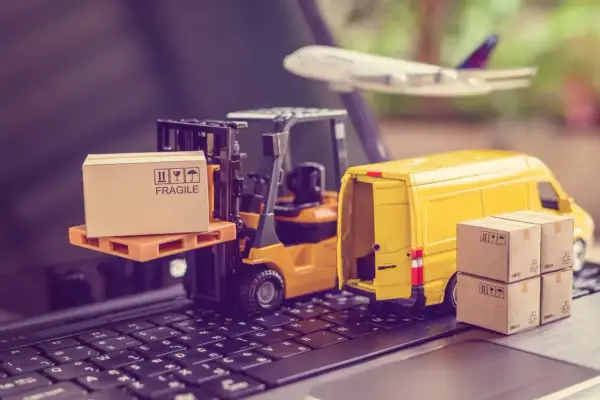 Miniatura ciężarówki, wózka widłowego i samolotu na klawiaturze z pudełkami.
